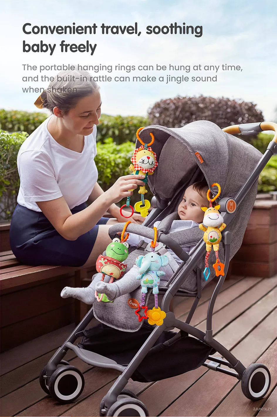 A mom pushing a stroller with a frog deer elephant lion toy hanging from it