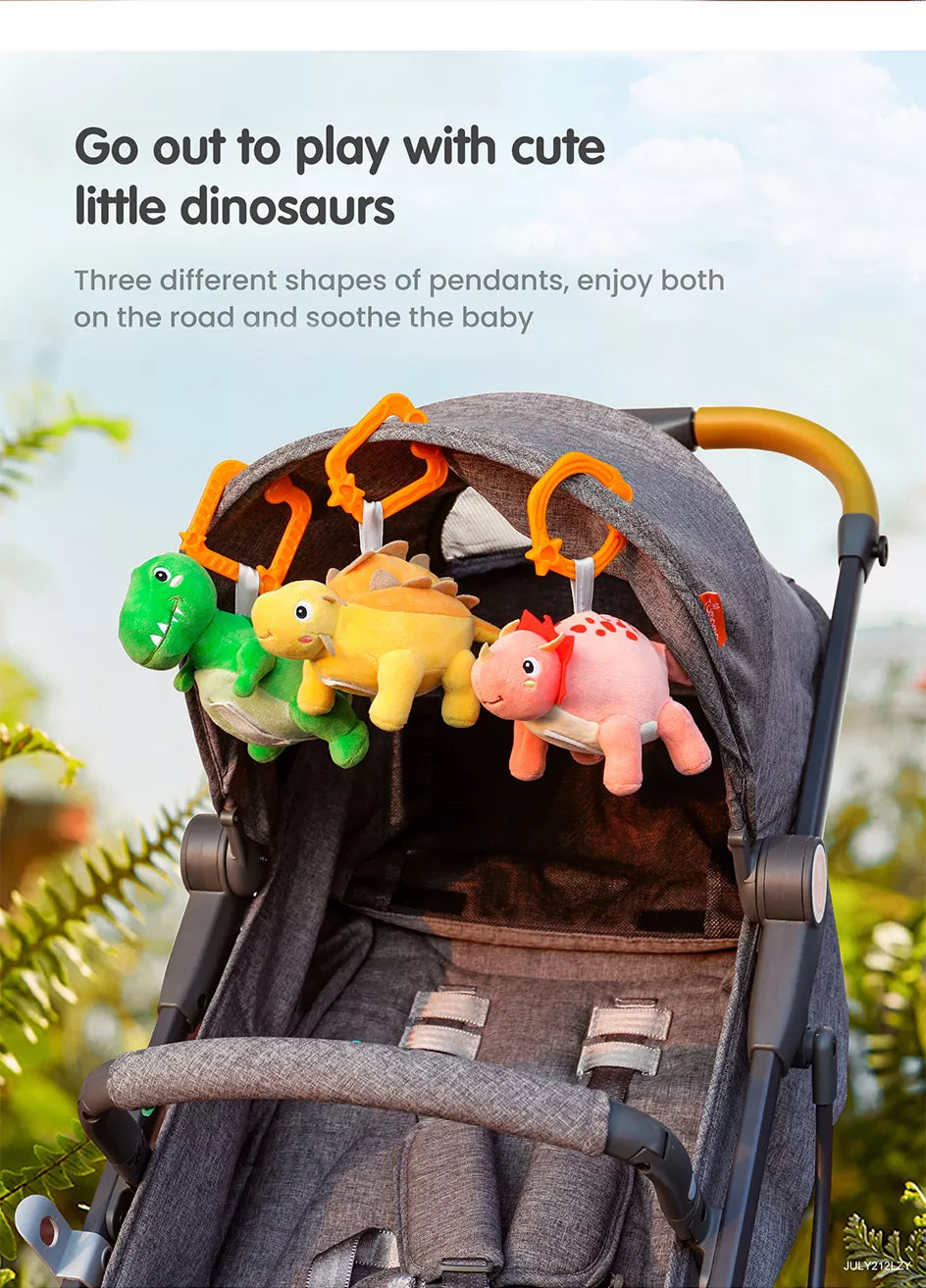 Baby stroller playing with several plush dinosaur toys hanging from it