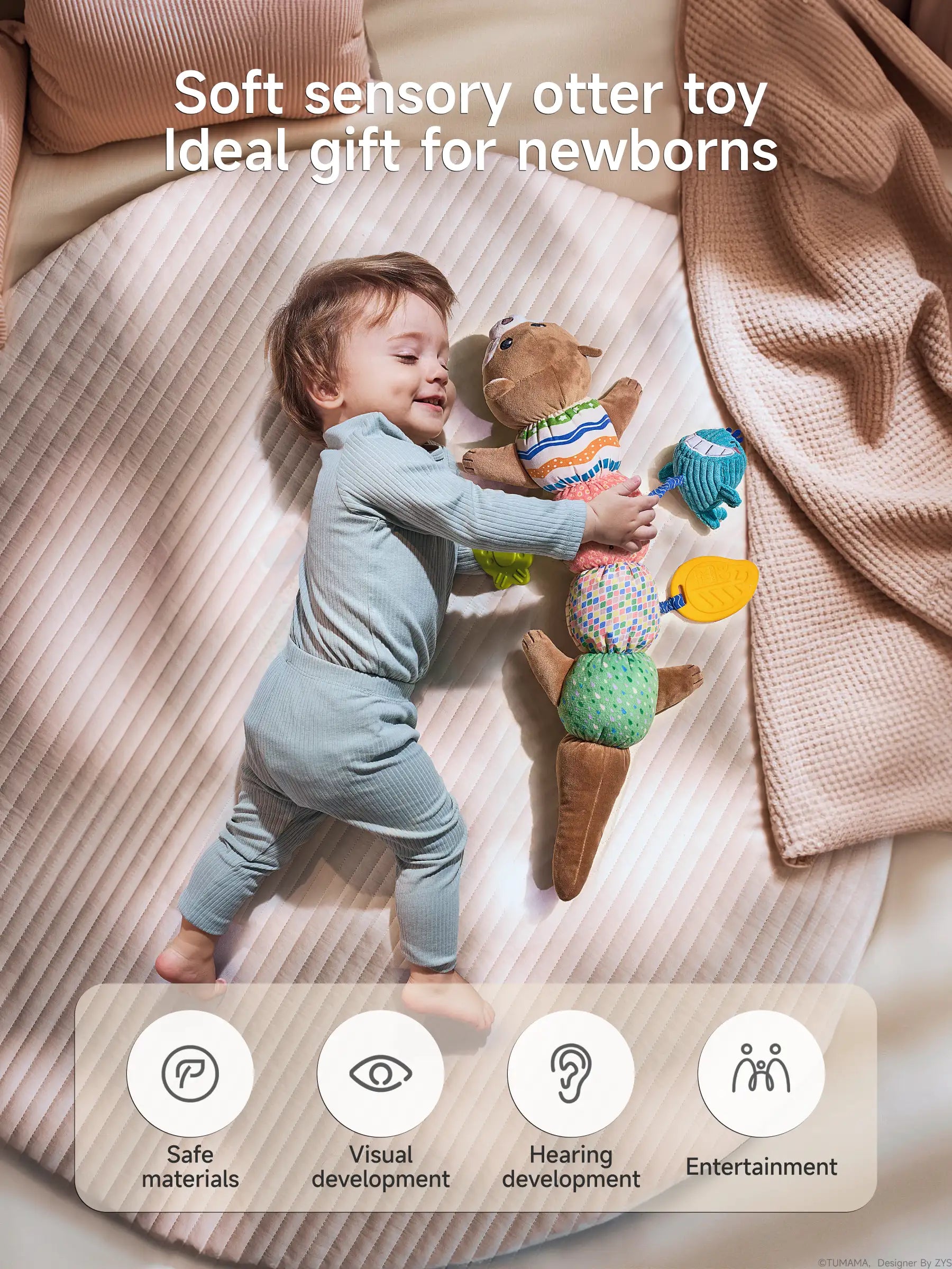 A promotional image of a baby in light blue ribbed clothing lying on a cream quilted surface, joyfully playing with a multifunctional sensory otter toy. The baby is smiling while reaching up to grasp the blue whale teether attached to the toy.