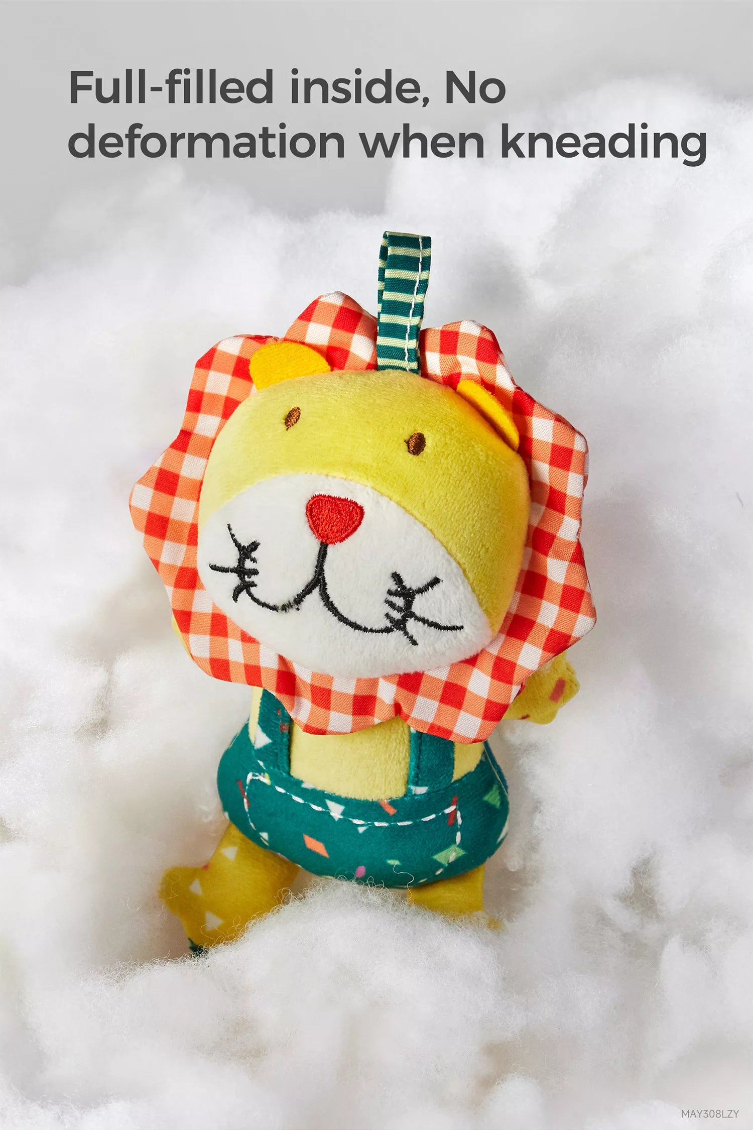 Close-up of a stuffed lion hanging rattle toy with a red gingham mane and teal overalls, shown resting on fluffy white filling to highlight its full, non-deforming stuffing.