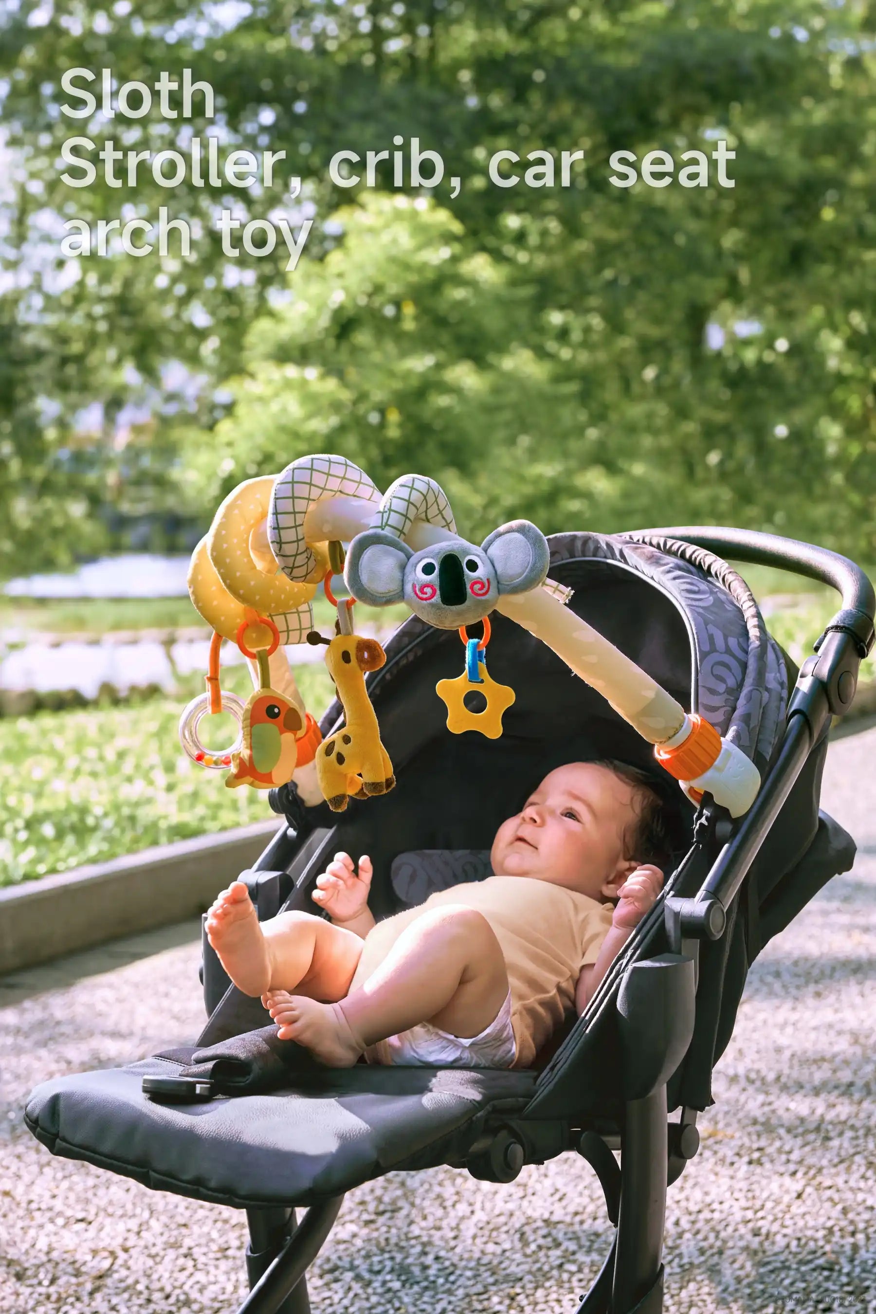 Outdoor baby playing with an arch toy in a stroller