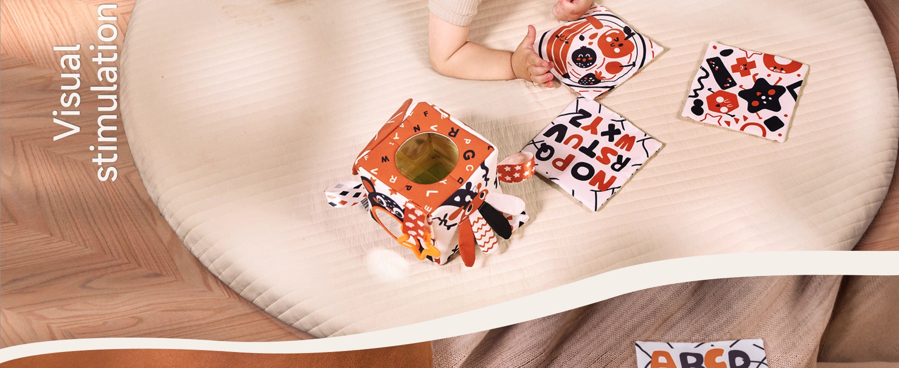 Baby playing with high-contrast sensory tissue box toy and soft flash cards on play mat for visual stimulation and early learning development
