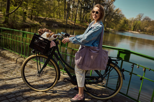 kobieta na rowerze z torbą sztruksową dla mam w kolorze fioletowym