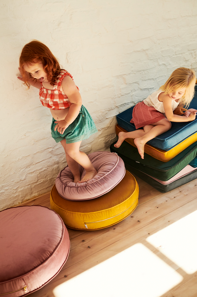 mała dziewczynka skacząca na pufach welurowych od bettys home dekoracja pokoju bliźniaków