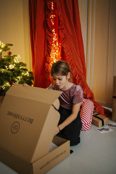 dziewczynka w trakcie świąt otwierająca prezent od bettys home - poduszka literka