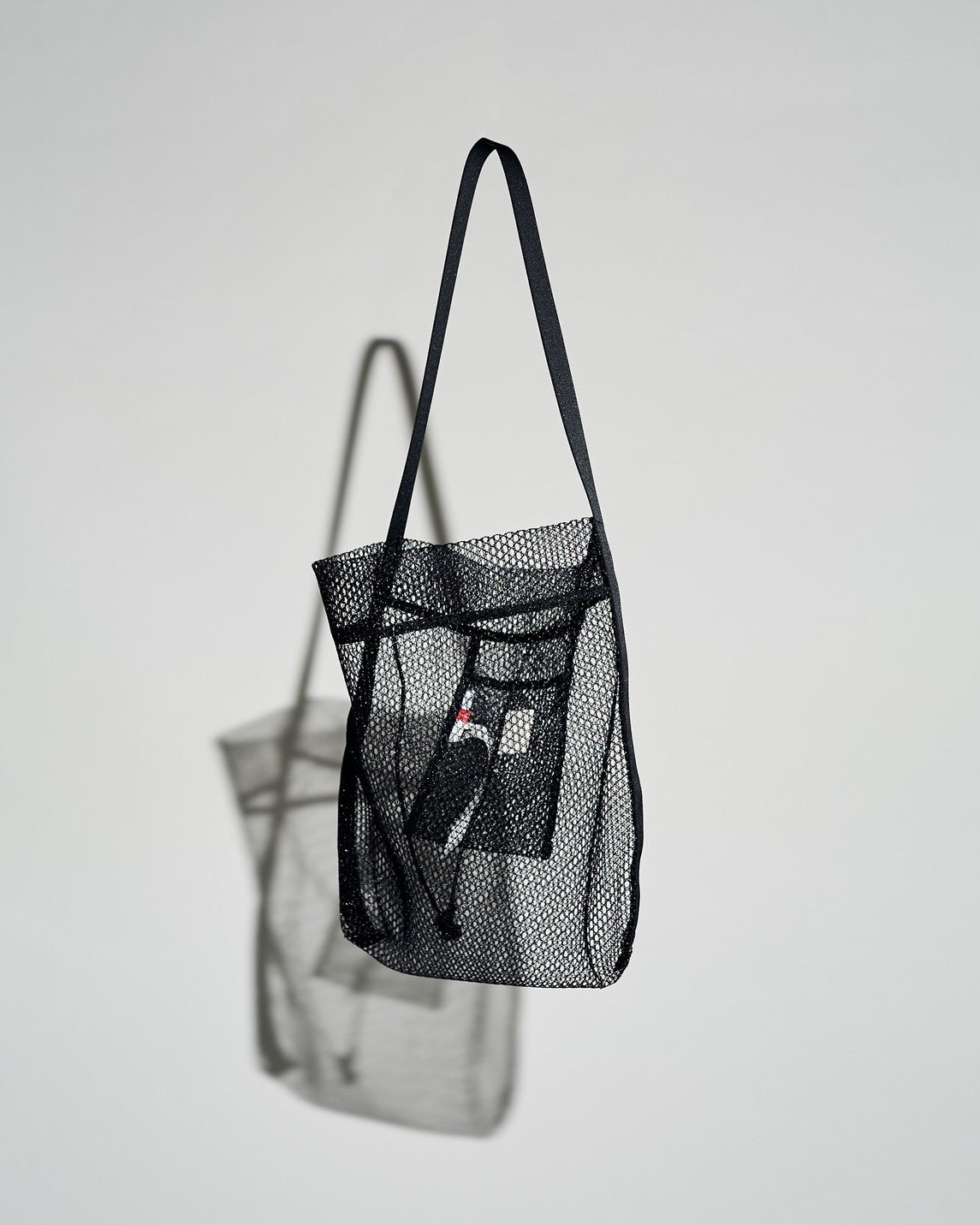 "AL for Graphpaper NYLON MESH TOTE"釣り糸に使用される透明色のナイロンテグスを特殊な染色方法で"漆黒"に染め上げ、鬘(カツラ)で有名なアデランスのネットなどを手がける京都の異色ニッターに制作を依頼。 通常のメッシュ素材よりも編みの組織や抜けを大きくすることで、”織”では表現できない"編"ならではの構造と表情が楽しめます。 しなやかで高強度のナイロンメッシュ素材を使用した、夏のカゴバックやキャンバスに変わる清涼感のあるトートバッグに仕上がりました。