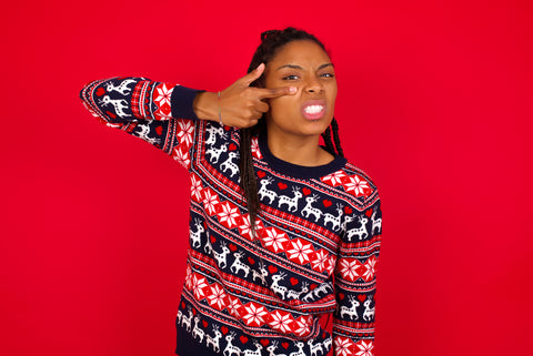 Christmas jumper wearing young woman pointing to a spot on her face