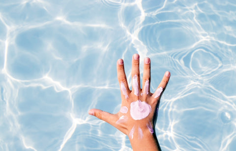 Suncream on a hand held over a swimming pool