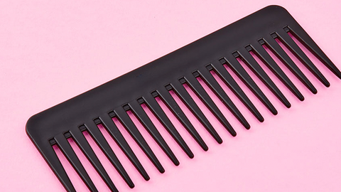 Girl combing her hair using wide-toothed comb 