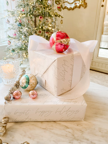 Adornos navideños antiguos con papel de regalo blanco y cinta de raso.