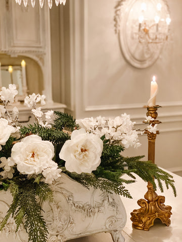 Jardinera vintage de hierro fundido con vegetación y rosas blancas y candelabros antiguos