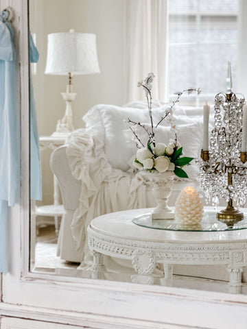 Pinecone flameless candle, antique candelabra and a white roses floral arrangement