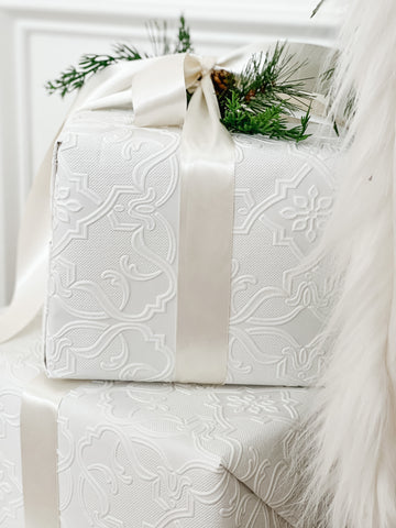 2 presents wrapped in white textured damask paper and ivory satin ribbon