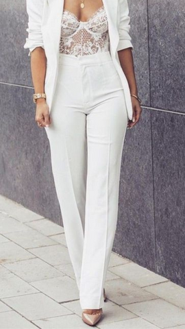 woman wearing white lace bustier bodysuit under formal white blazer and pants