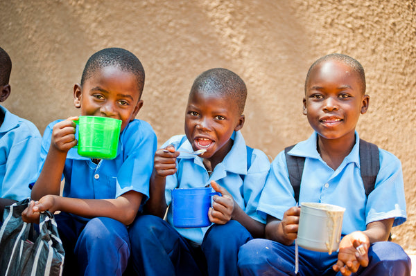 tres meninos africanos a beber agua em chavenas de plastico