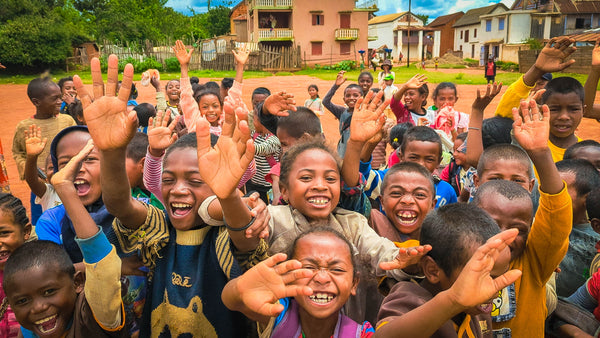 Muitos meninos e meninas na Africa com os braços no ar e sorridentes