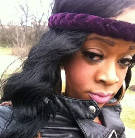 Selfie of Deoni Jones, Black Transgender woman, wearing a velvet purple headband, gold hoops, and a black leather jacket. 