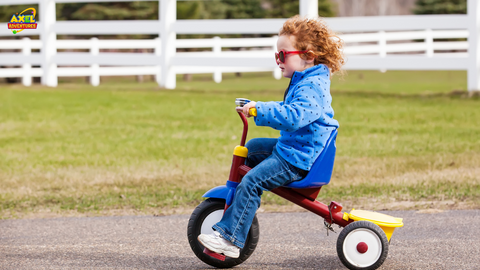 A young child riding a tricycle, promoting motor development in early childhood through physical activity and play.
