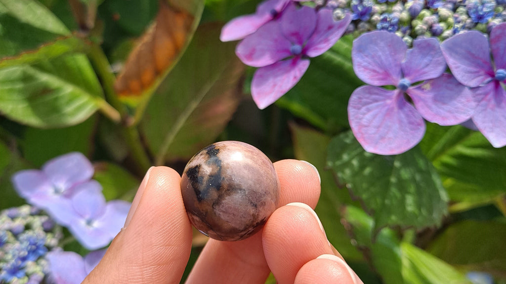image of a rhodonite mini sphere. this healing crystal is available at dumi's crystals