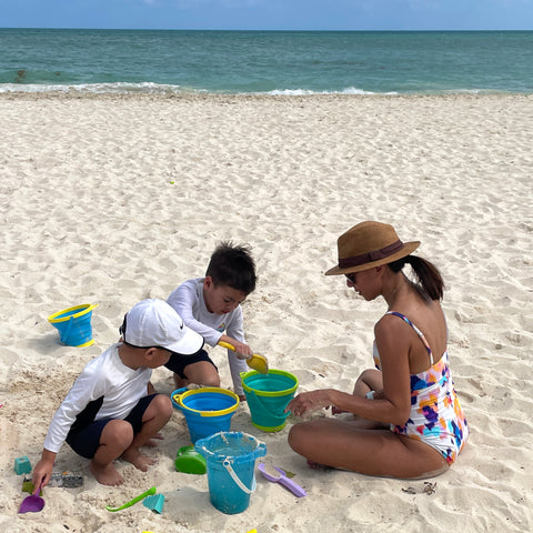 mom with little boys on the beach and sand toys and pails