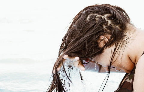 Girl wringing out hair after swimming in the ocean