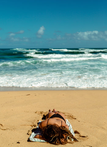 Girl laying on the beach suntanning