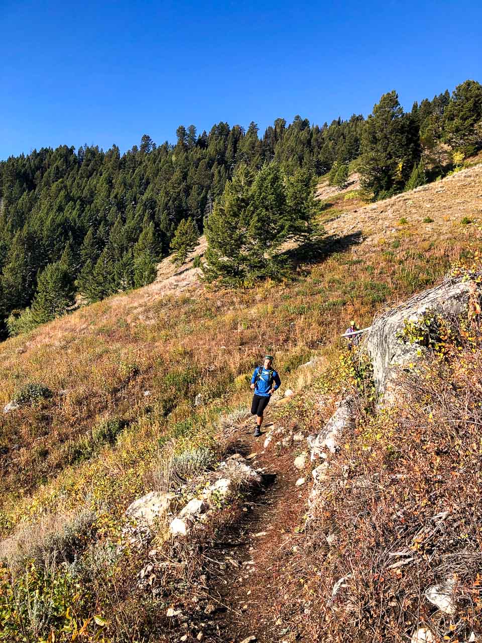 Men running down a trail in the mountains