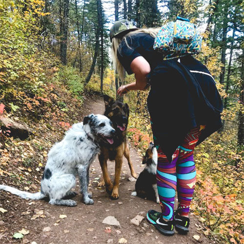 A woman and two dogs on a trail in the woods
