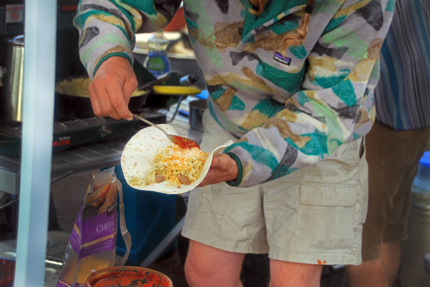 Man is adding sauce to a burrito