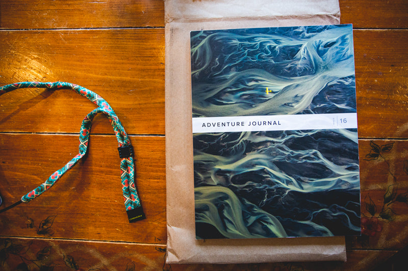 Adventure Journal Magazine next to a Croakies eyewear strap