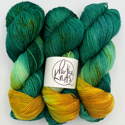 Aquatic, a green and gold variegated skein of yarn by Partea Knits