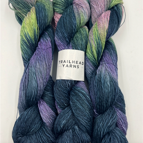 A skein of hand-dyed Trailhead yarn in dark blue, bright green, pink, and purple.