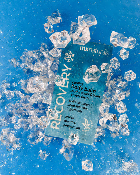 a white and blue product titled "recovery cooling body care balm"  is submerged under icy cold water to represent the chill of the product.