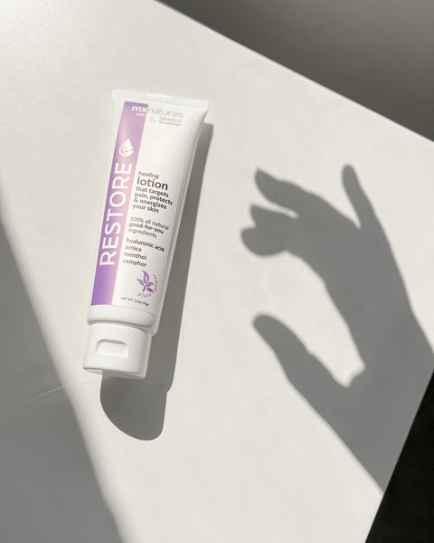 restore targeted healing lotion on a table top with the shadow of a hand reaching out for the product