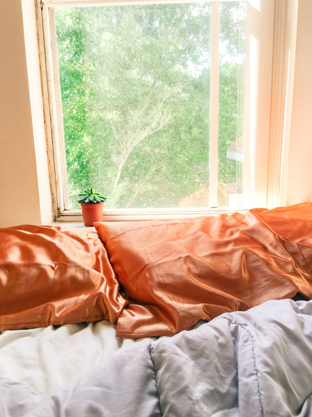 early morning haze over unmade bed with orange pillow cases