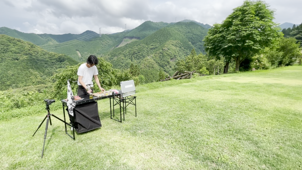 自然豊かな原っぱで調理する平川さん