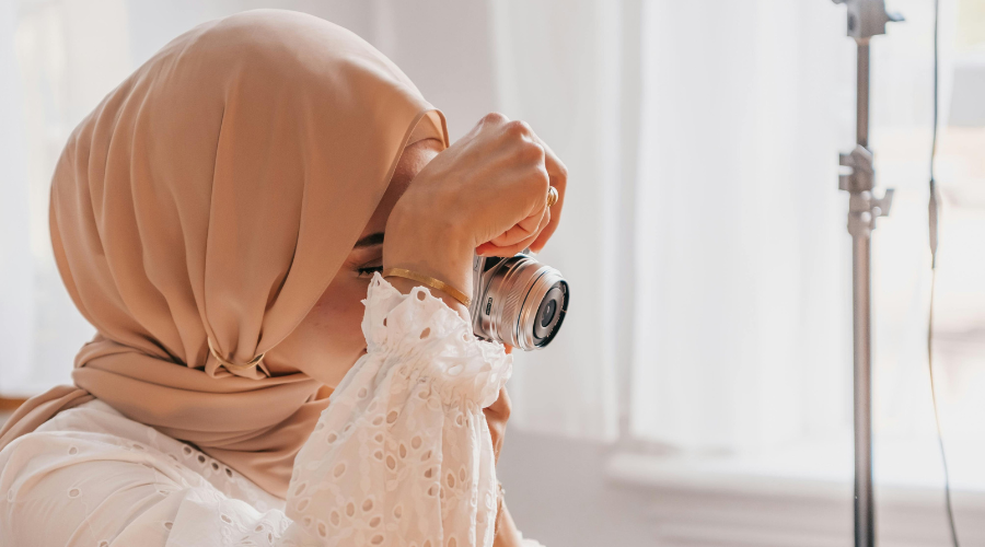 woman in white dress and peach hijab taking photos