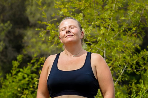 Jeune femme dans la nature fermant les yeux et souriant