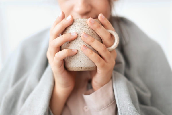 Jeune femme buvant une tisane pour apaiser les douleurs de règles