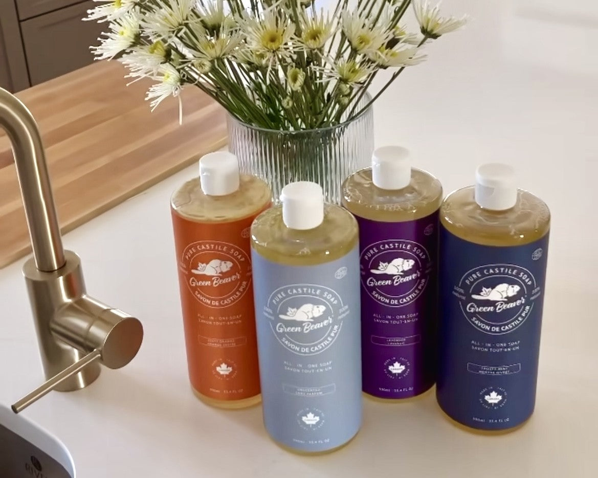 Bottles of Green Beaver's Castile soap sit on a kitchen counter beside vase of flowers