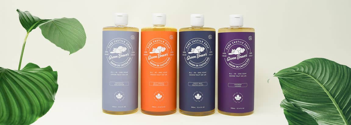 Four of Green Beaver's pure liquid Castile soap are on a beige background surrounded by green leaves.