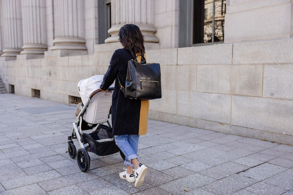 Mom with a Fawn Design diaper bag pushing a stroller in a city
