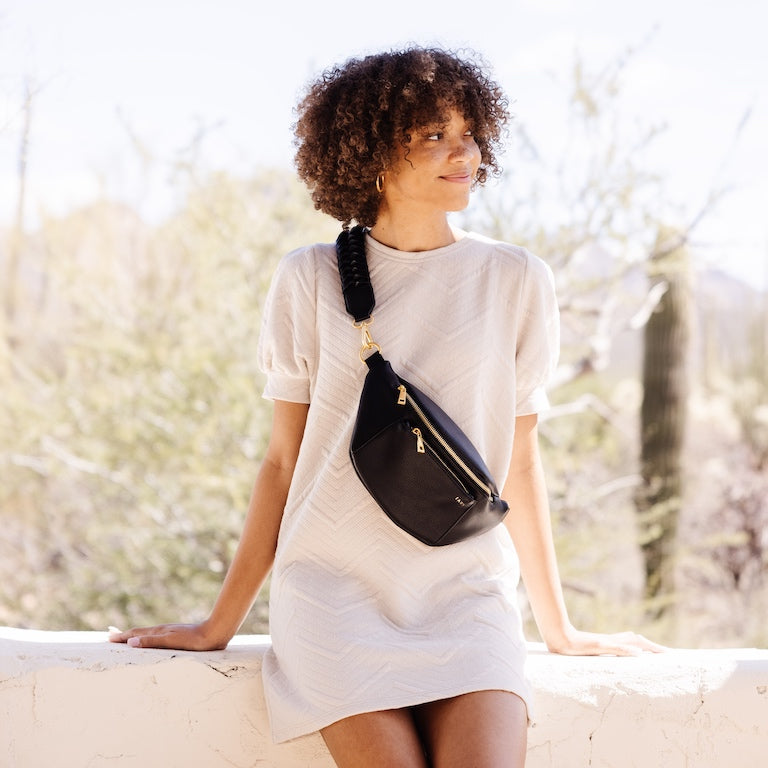 woman wearing a fawn design fanny pack leaning on a wall