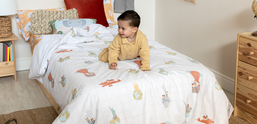 Niño pequeño sobre cama con diseño World Trip