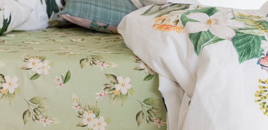 Detalle de sábana bajera verde floreada en cama deshecha