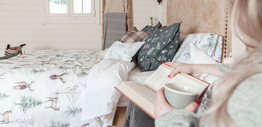 chica leyendo con taza en la mano en una habitación invernal