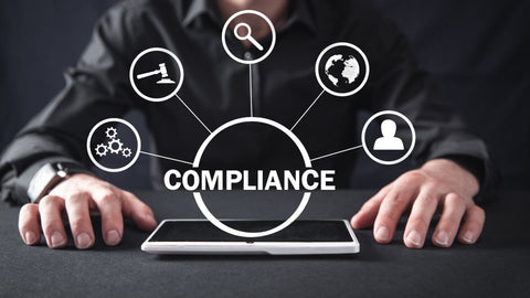 The word compliance and icons related to that hovering over a screen on a table