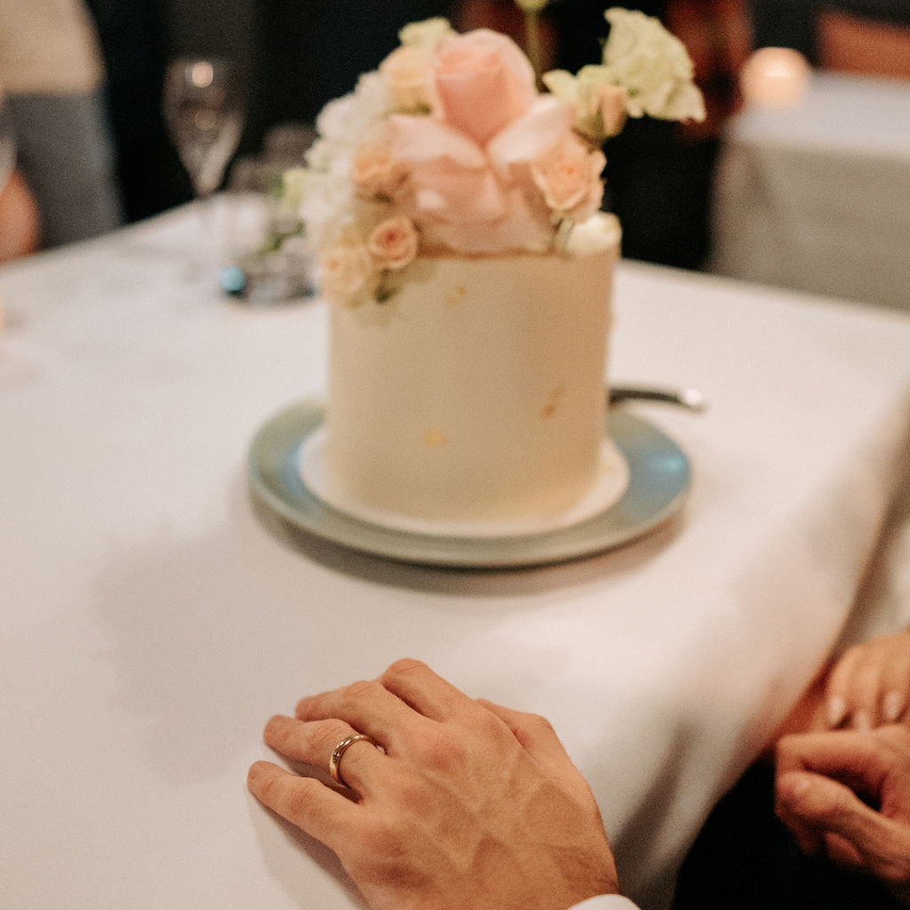 Wedding cake and Grooms wedding ring on hand