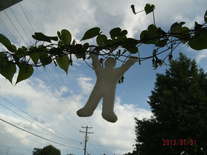 Car antenna decoration in the shape of a person made with InstaMorph moldable plastic shown hanging from a tree branch.