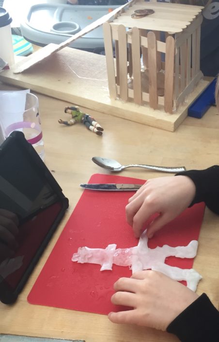 Kid's hands shown molding InstaMorph moldable plastic into a leprechaun shape for a school project.